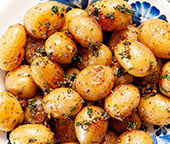 A blue and white bowl filled with roasted baby potatoes.