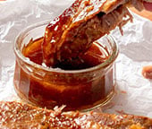 Dipping a pork rib in a Cajun glaze.