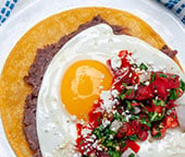 Huevos rancheros on a blue striped napkin.
