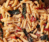 Brown butter sage pasta with bacon in a silver skillet.
